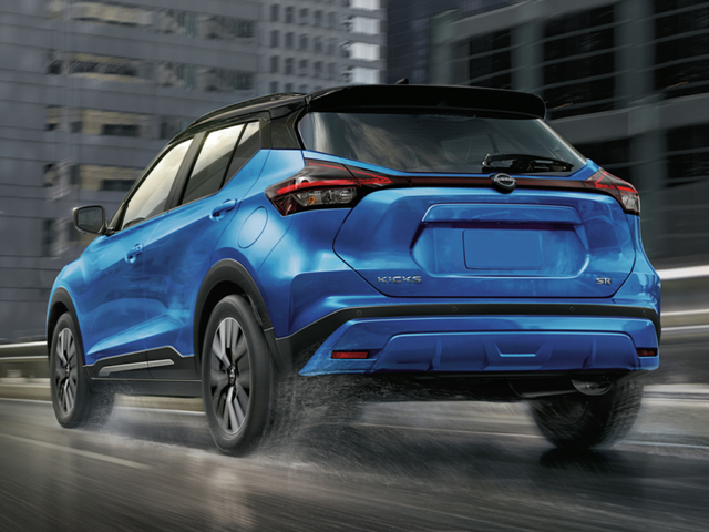 Rear profile view OF A BLUE 2024 Nissan Kicks being driven on the road in the rain. | Nissan dealer in Altoona, PA | Courtesy Nissan PA