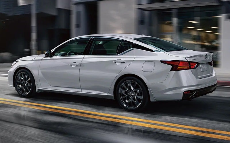 White Nissan Altima driving on street